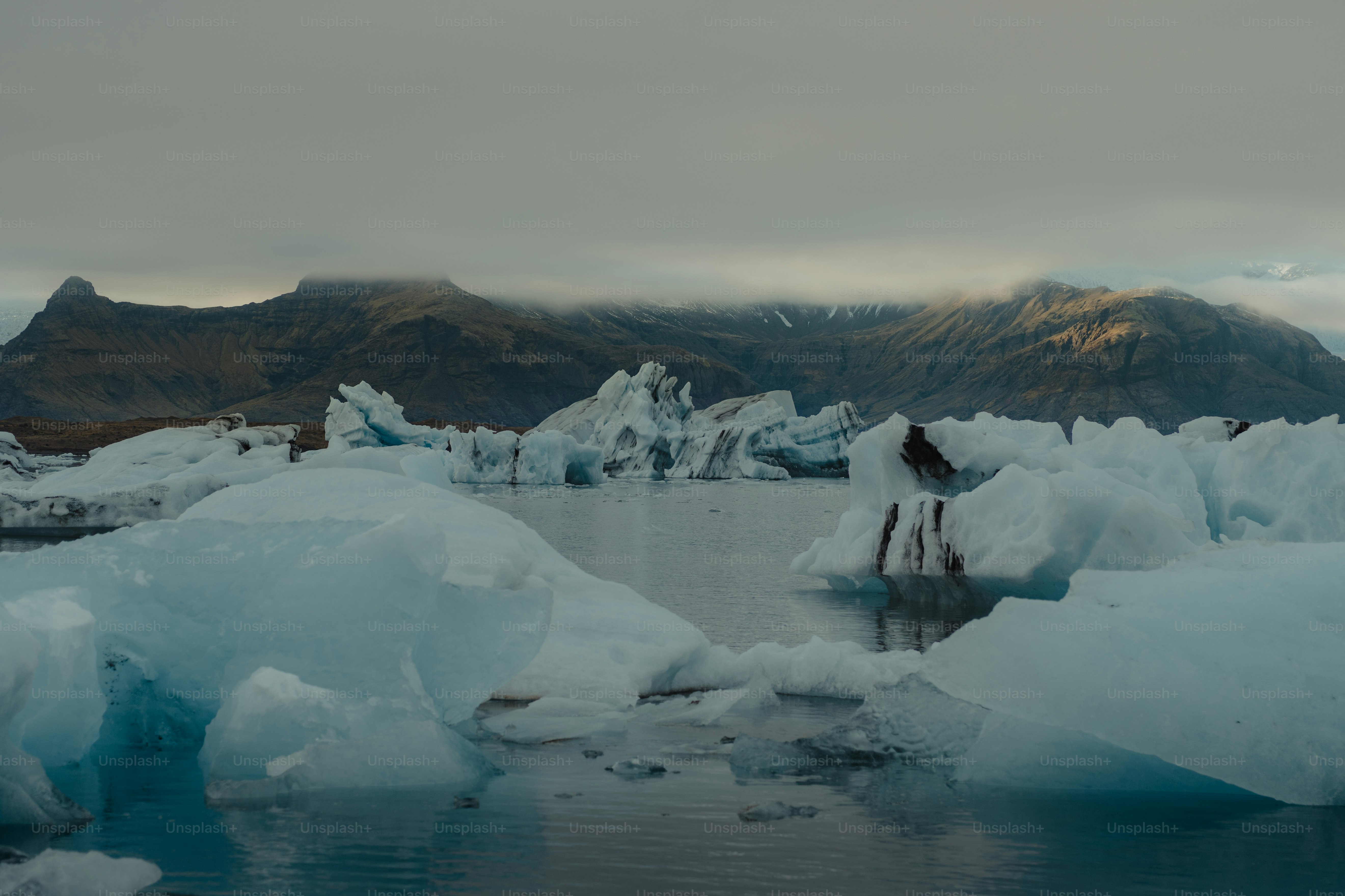 a body of water surrounded by snow covered mountains