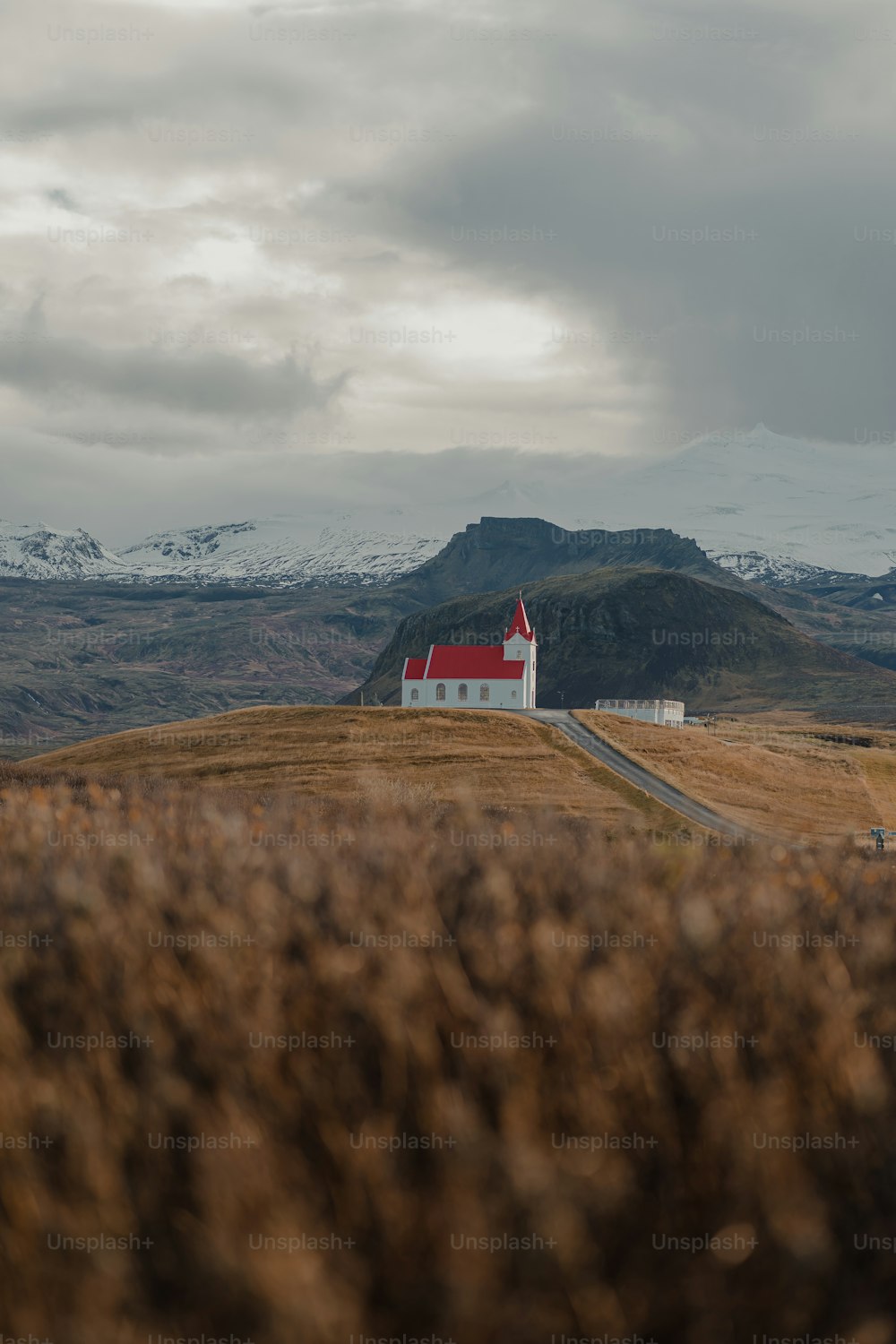 Una casa roja y blanca en una colina con montañas al fondo