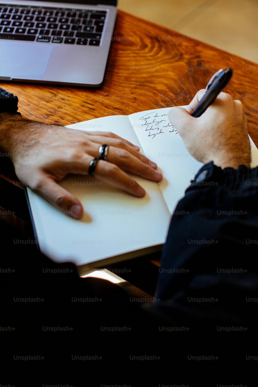 a person writing on a notebook with a pen