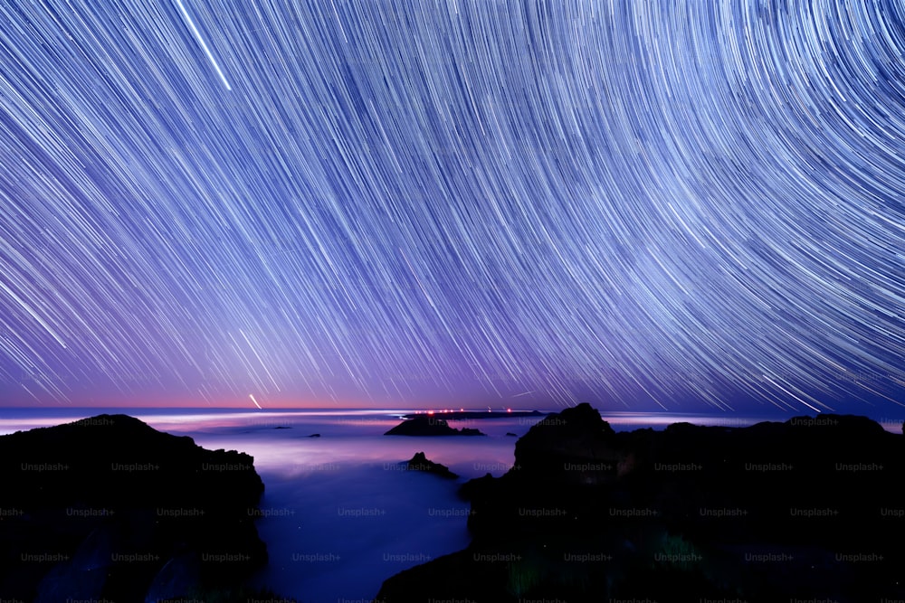 a star trail is seen in the sky above the ocean