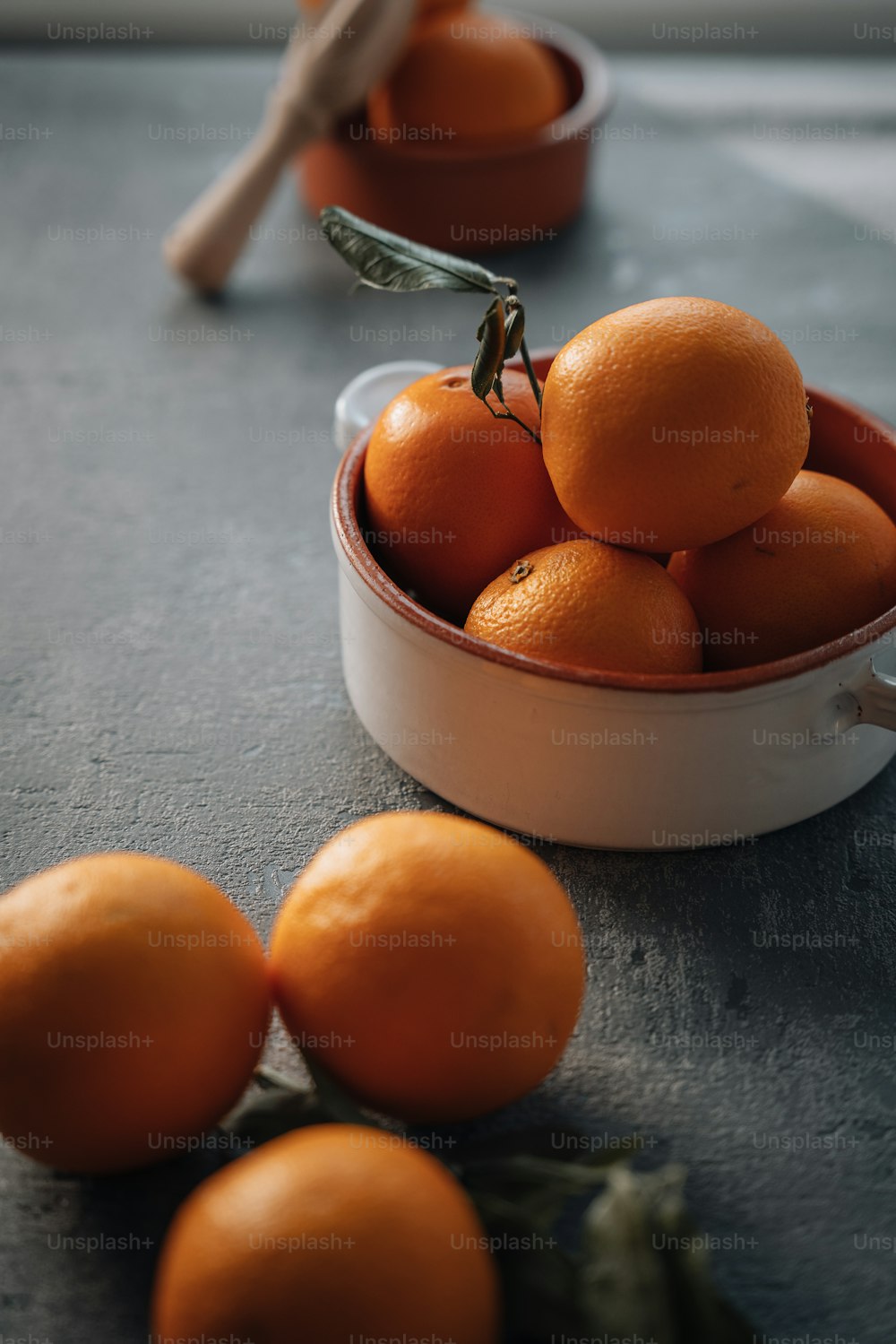 Un tazón blanco lleno de naranjas encima de una mesa
