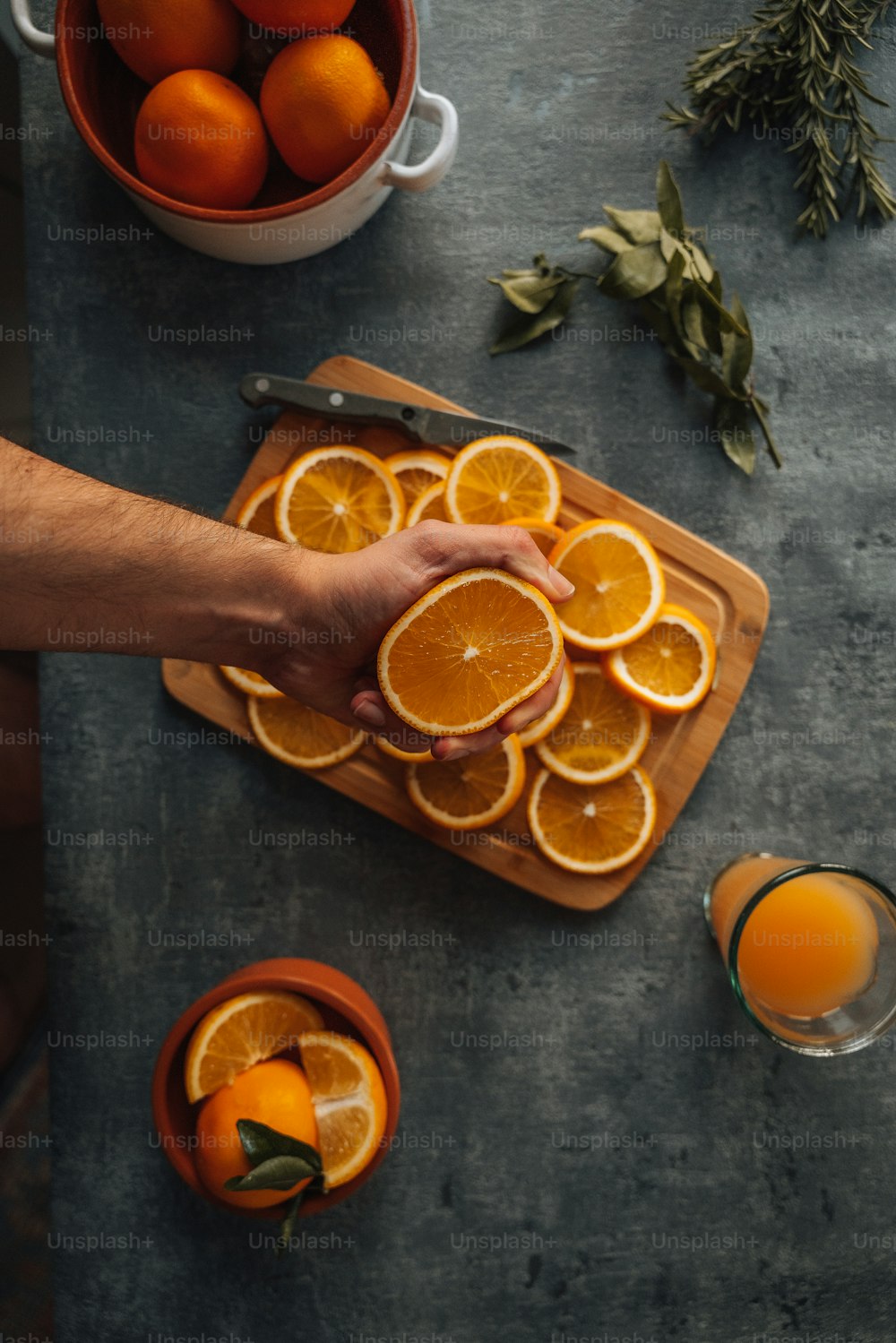 une planche à découper garnie d’oranges tranchées à côté d’une tasse de jus d’orange