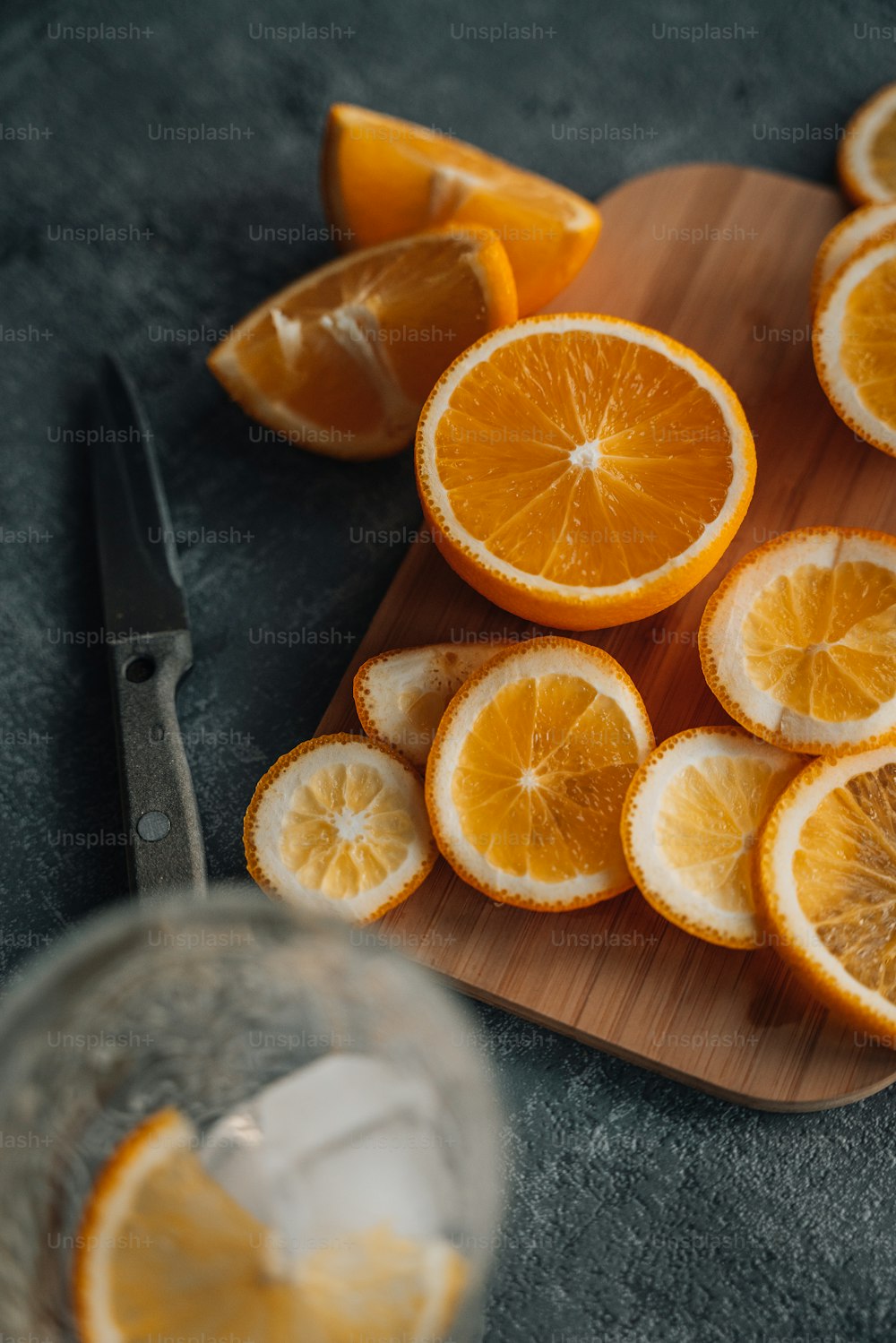 una tabla de cortar cubierta con naranjas en rodajas junto a un cuchillo