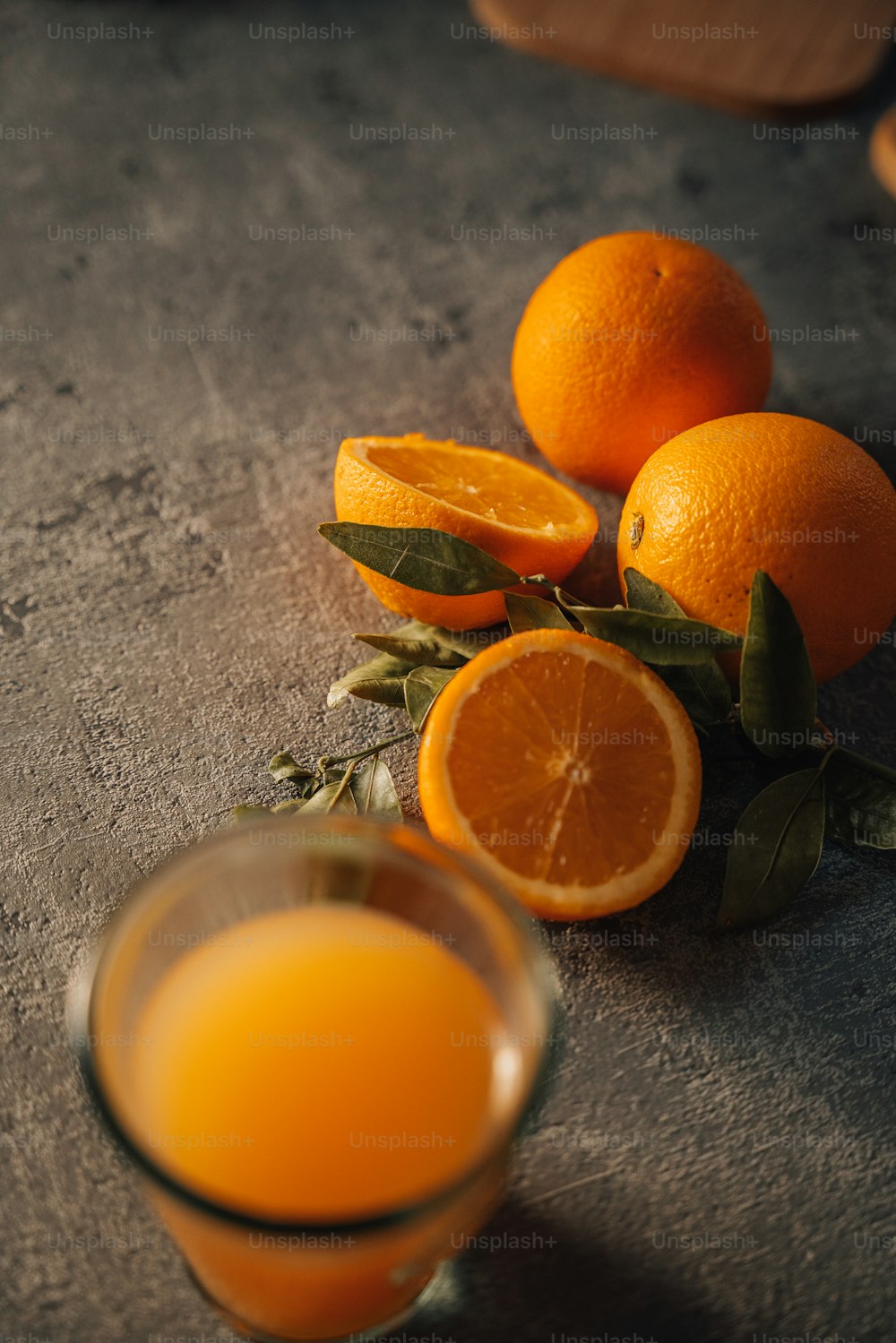 a glass of orange juice next to some oranges
