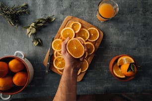 Una persona sosteniendo una naranja sobre una tabla de cortar