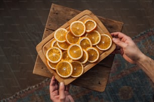 a person holding a cutting board with sliced oranges on it