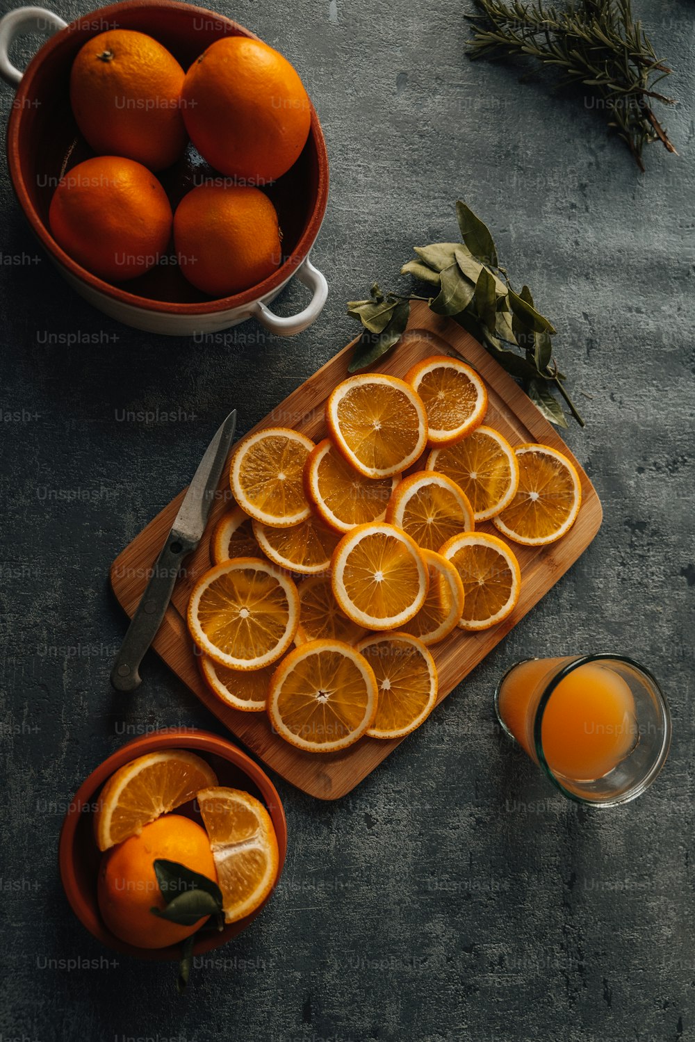 uma tábua de corte coberta com laranjas fatiadas ao lado de uma tigela de laranjas