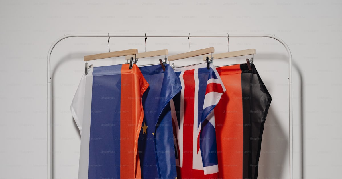 Three flags hanging on a clothes rack in a room photo – Countries Image ...