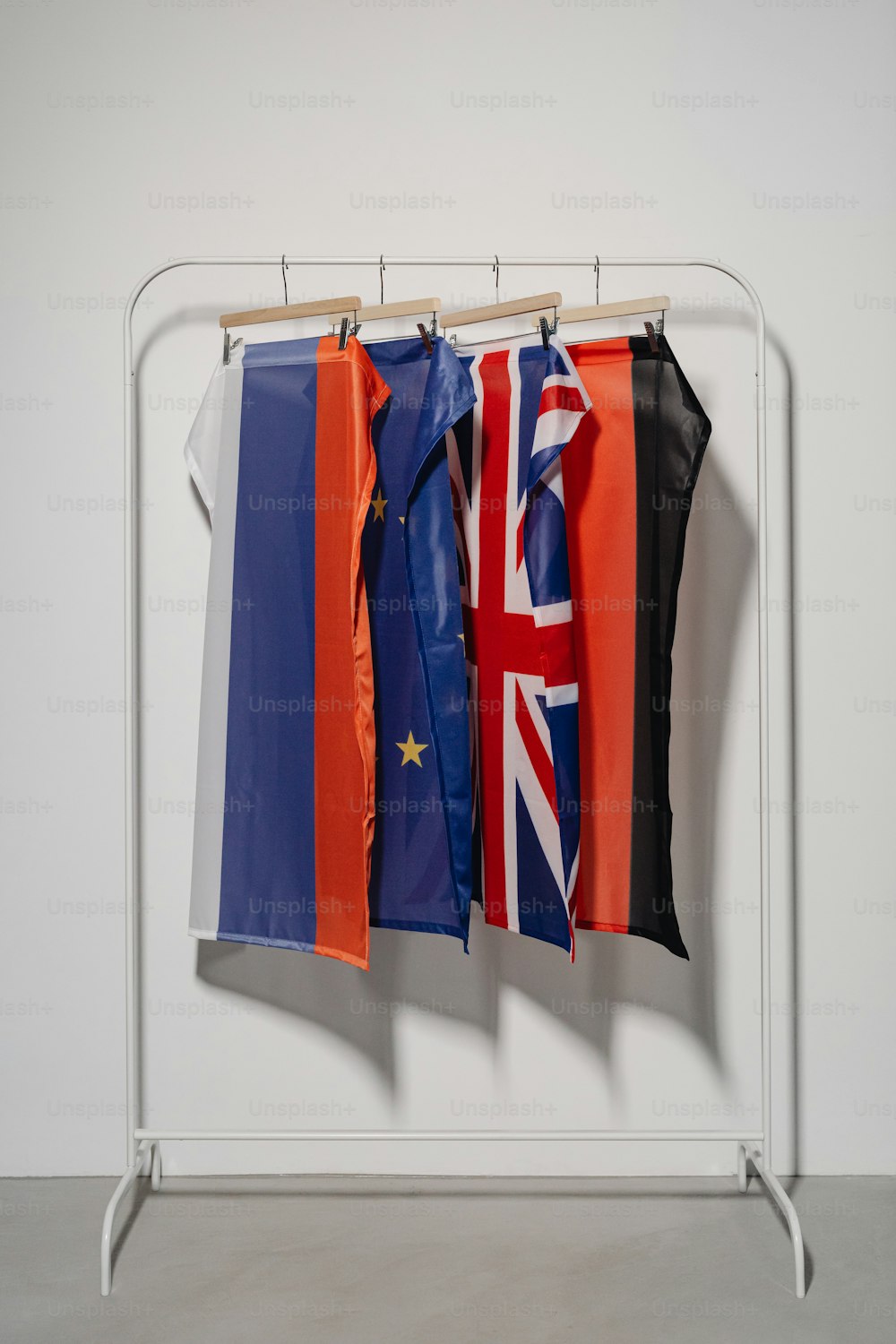 three flags hanging on a clothes rack in a room