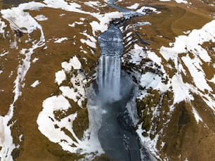 Luftaufnahme eines Wasserfalls umgeben von Schnee