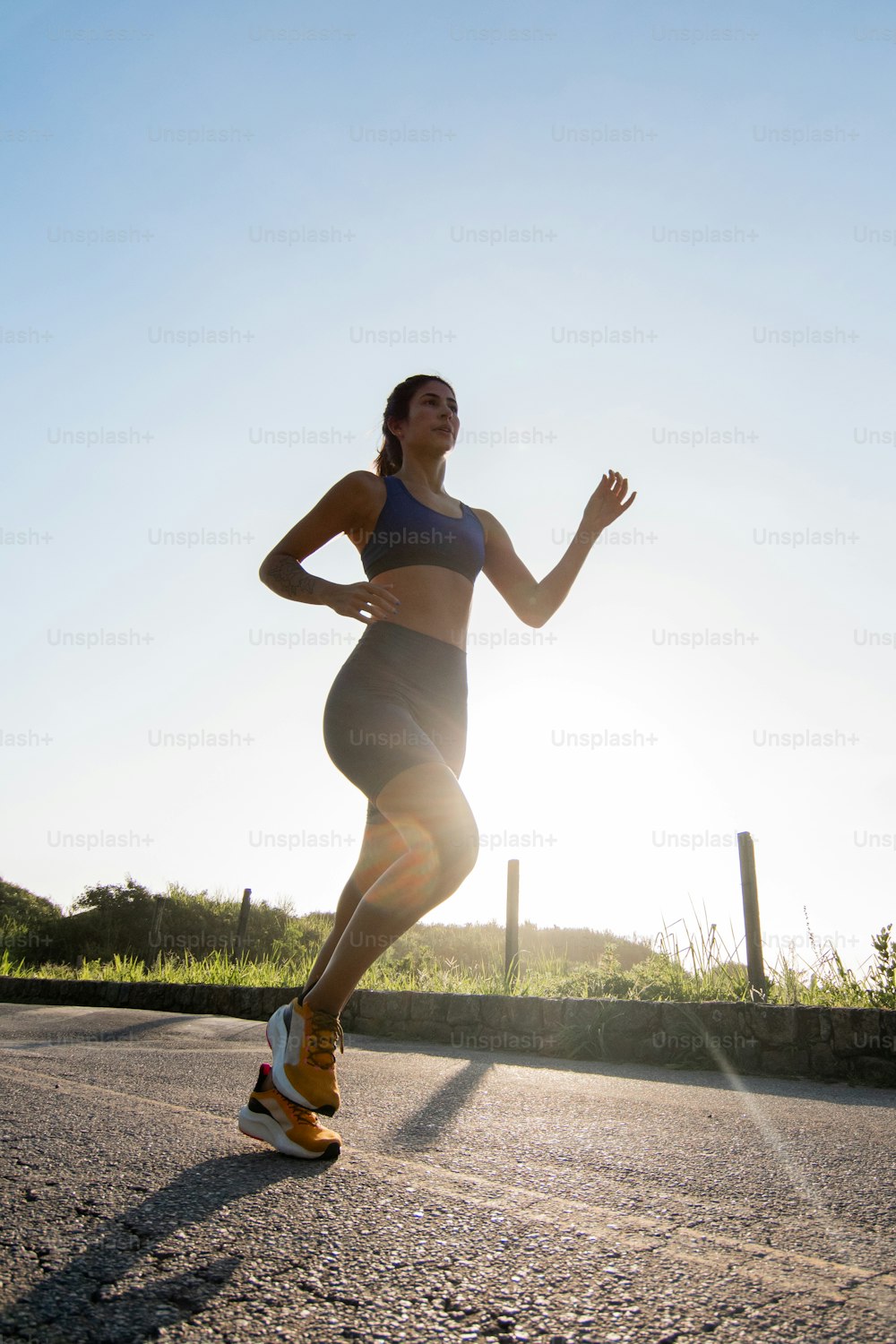 uma mulher correndo em uma estrada ao sol