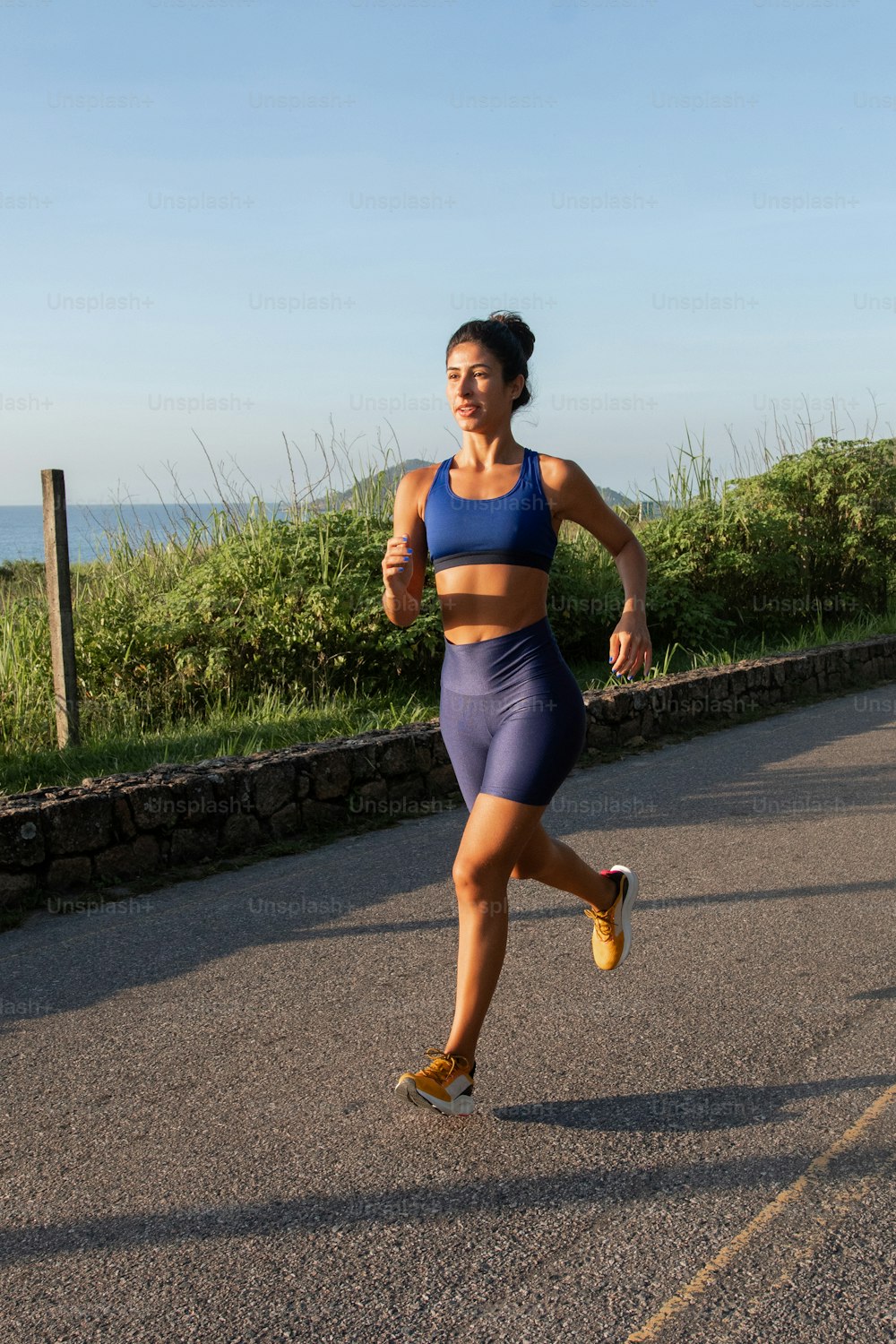 a woman running down a road in a sports bra top