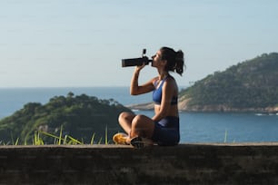 a woman sitting on a ledge looking through a telescope