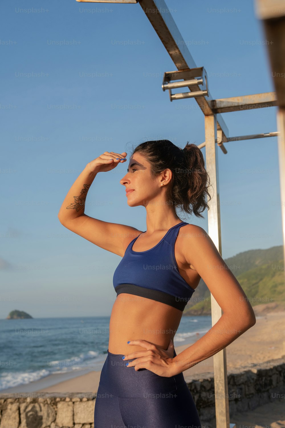 a woman in a blue sports bra top standing on the beach