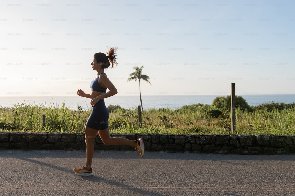 a woman running down a road near the ocean
