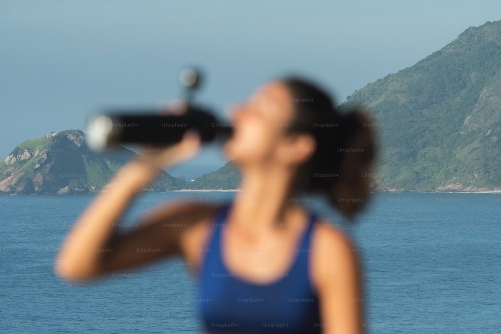 a woman in a blue top drinking from a water bottle