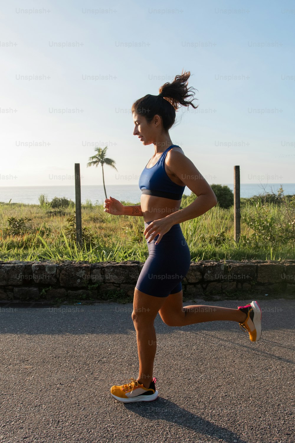 uma mulher correndo em uma estrada perto do oceano