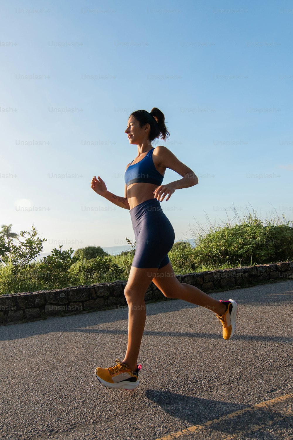 a woman running down a road with a sky background