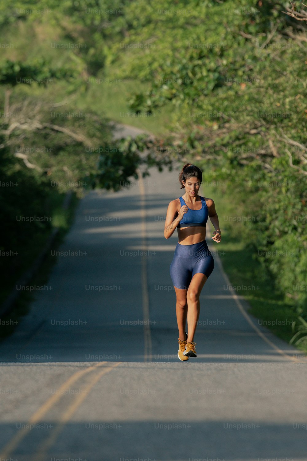 a woman running down a road with trees in the background