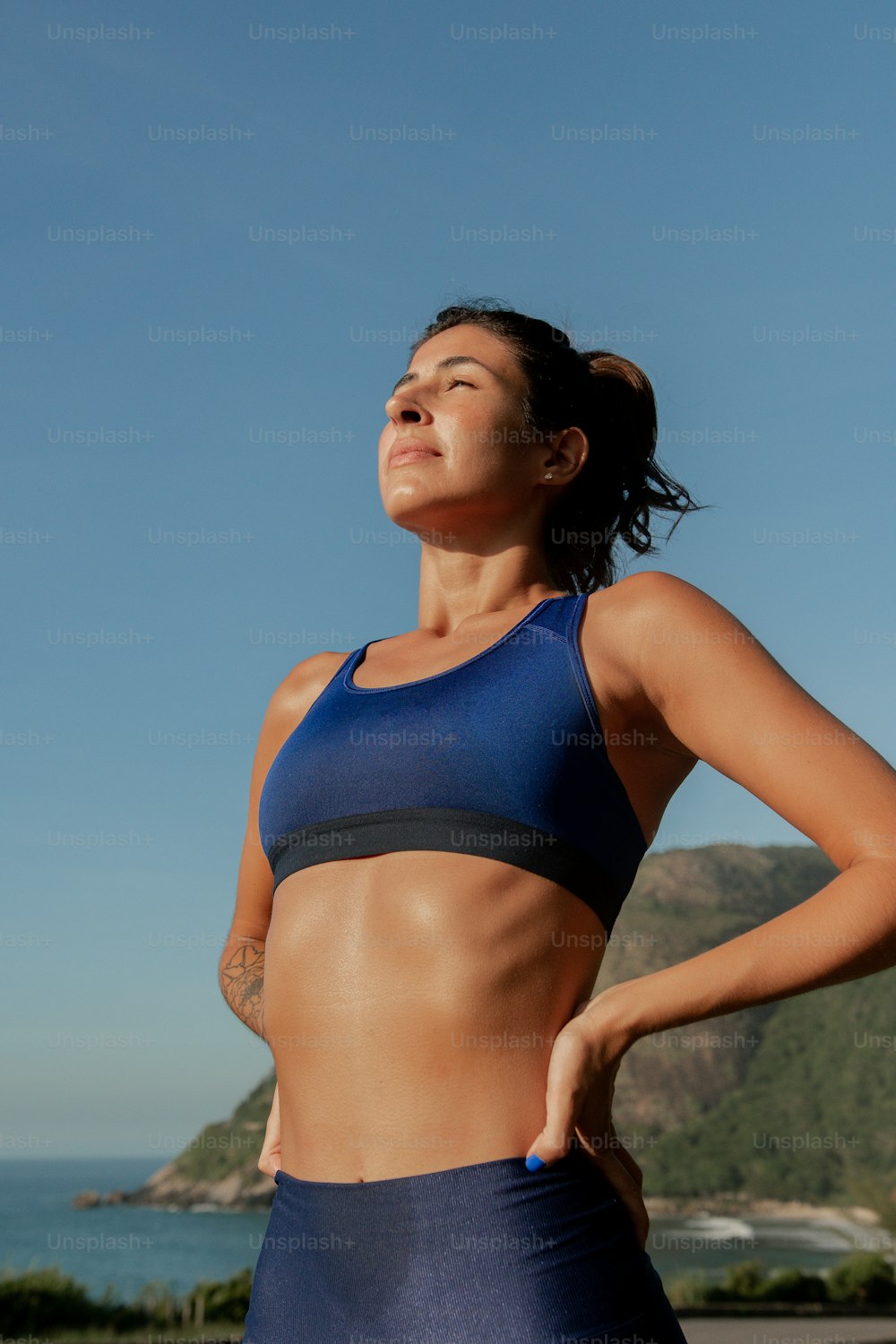 a woman in a blue sports bra top standing in front of a body of water