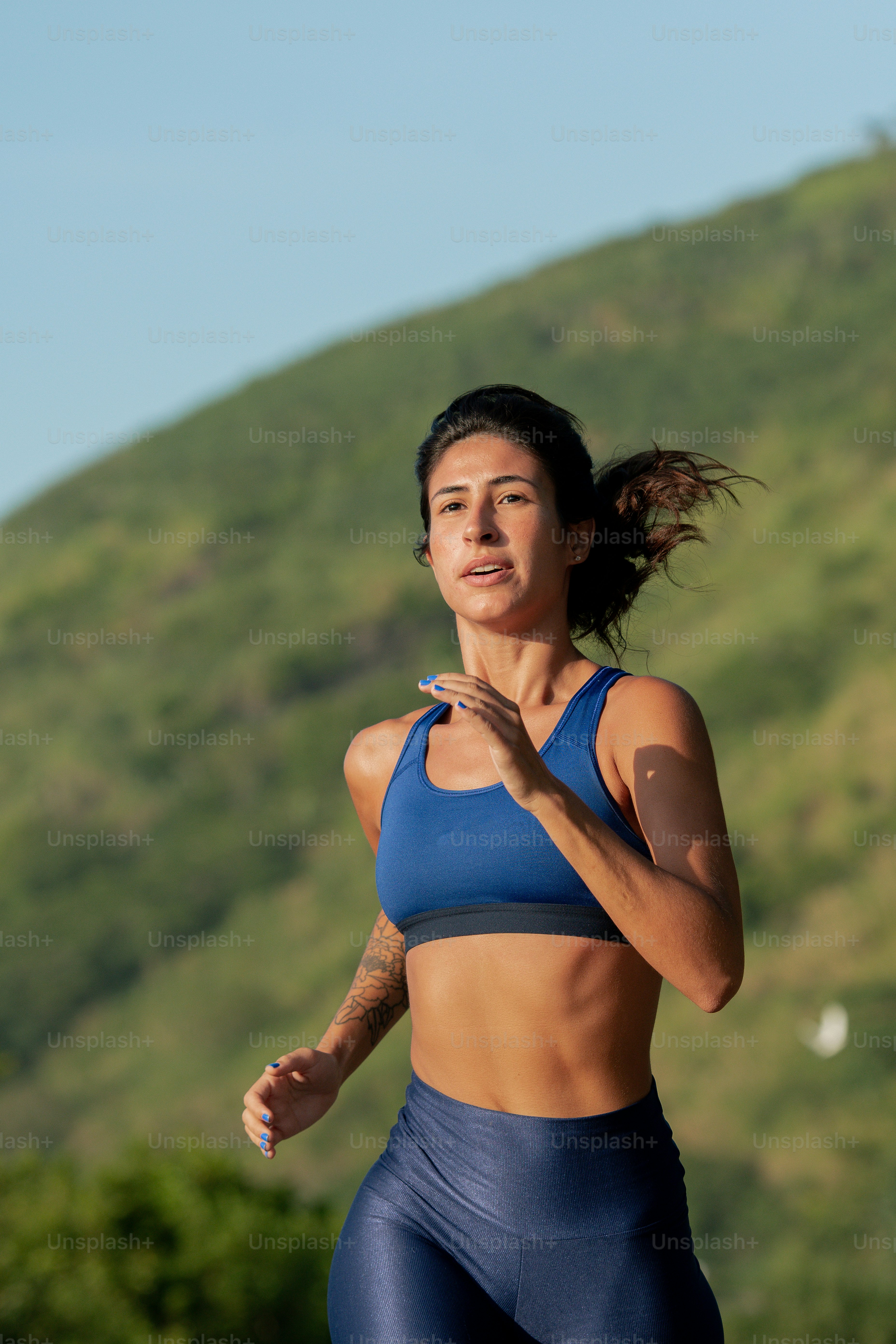 青いスポーツブラトップで走る女性