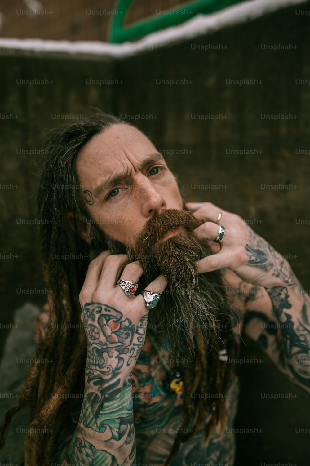 Un homme aux cheveux longs et aux tatouages sur le visage
