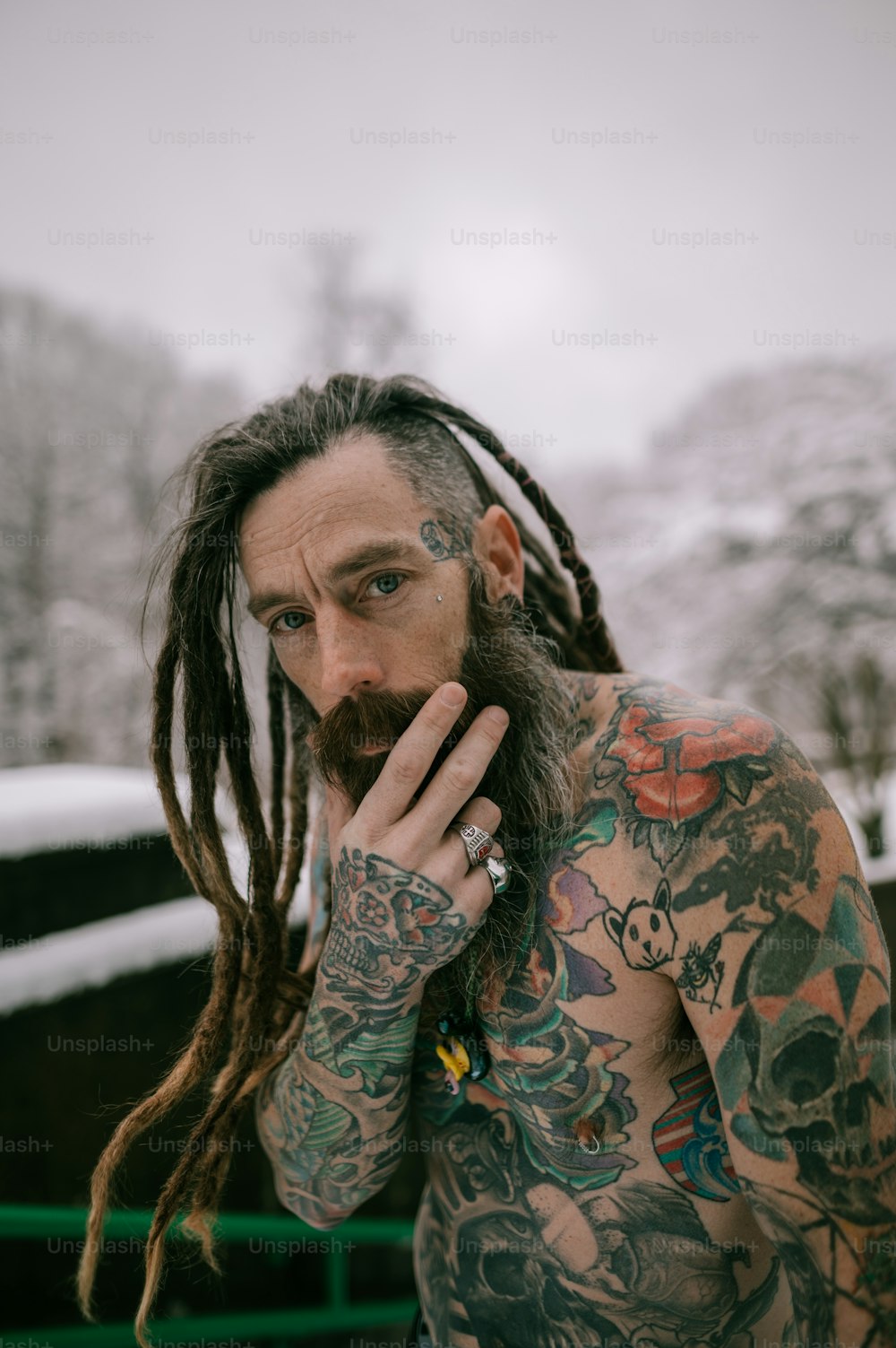 um homem com longos dreadlocks e tatuagens no rosto