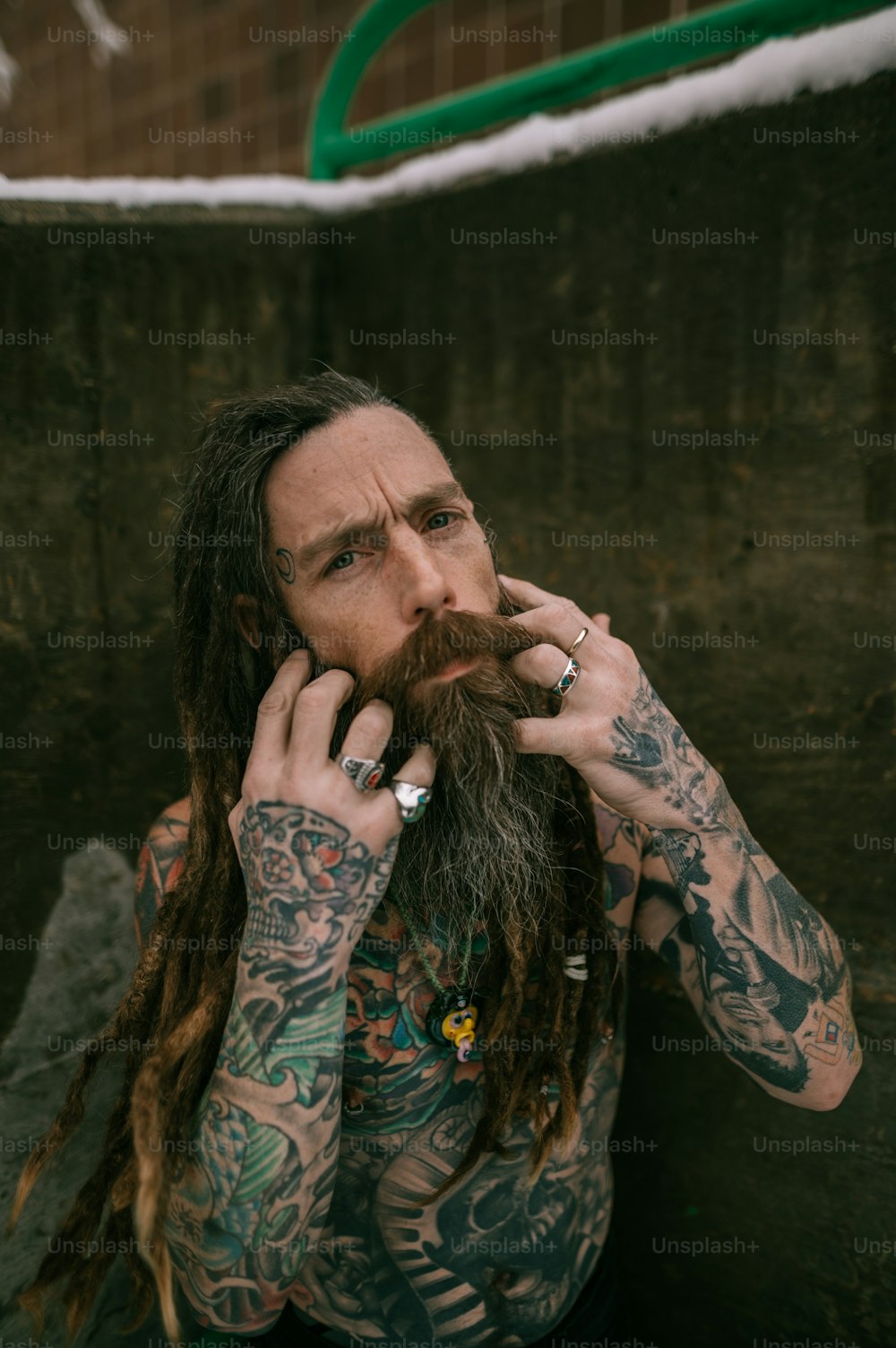 a man with long hair and tattoos on his face talking on a cell phone