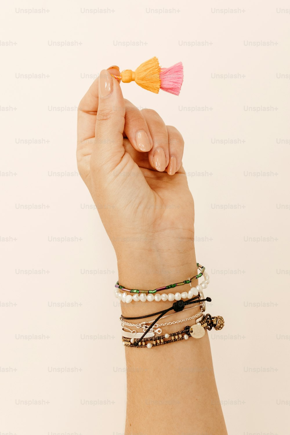 a hand holding a bracelet with a tassel