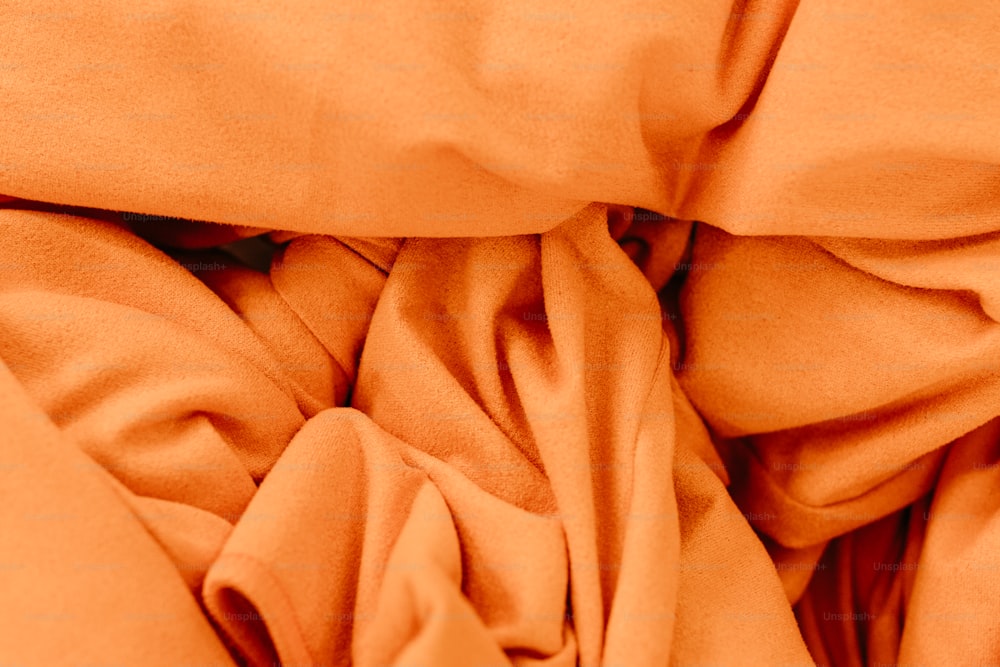 Eine Nahaufnahme eines Bettes mit orangefarbenen Laken