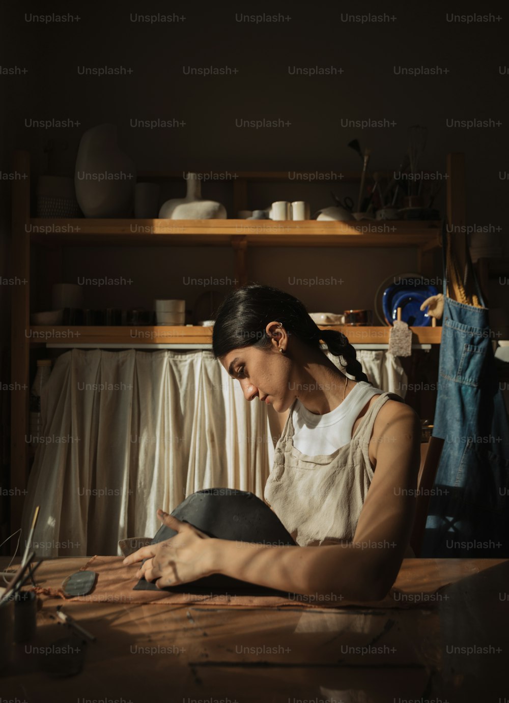 a woman sitting at a table working on a hat