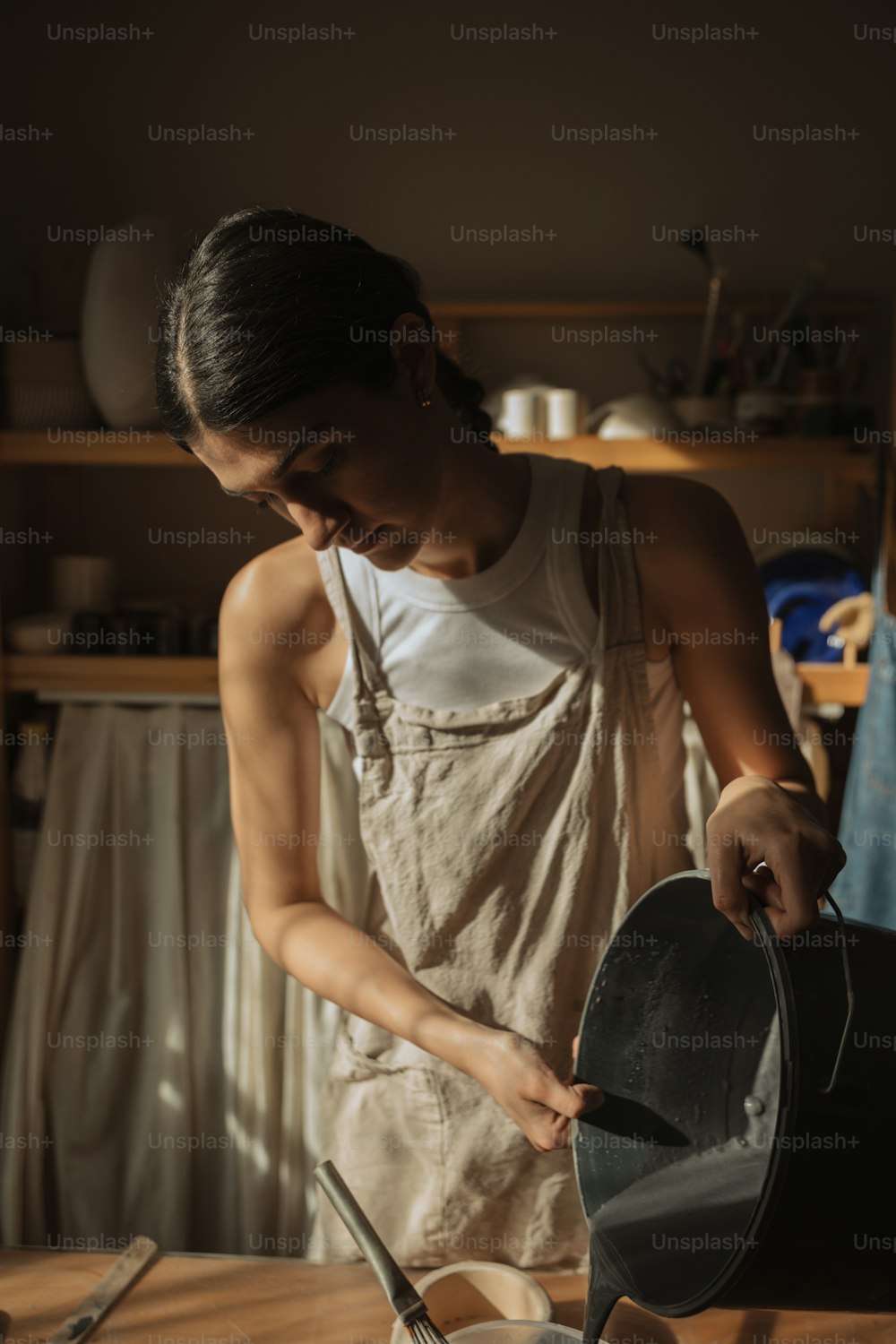 Une femme en tablier travaille sur un pot