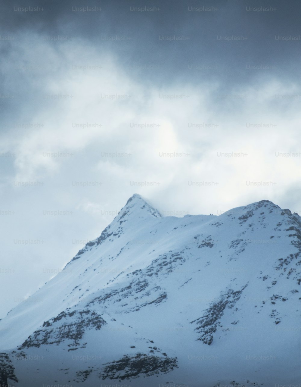 a snow covered mountain under a cloudy sky