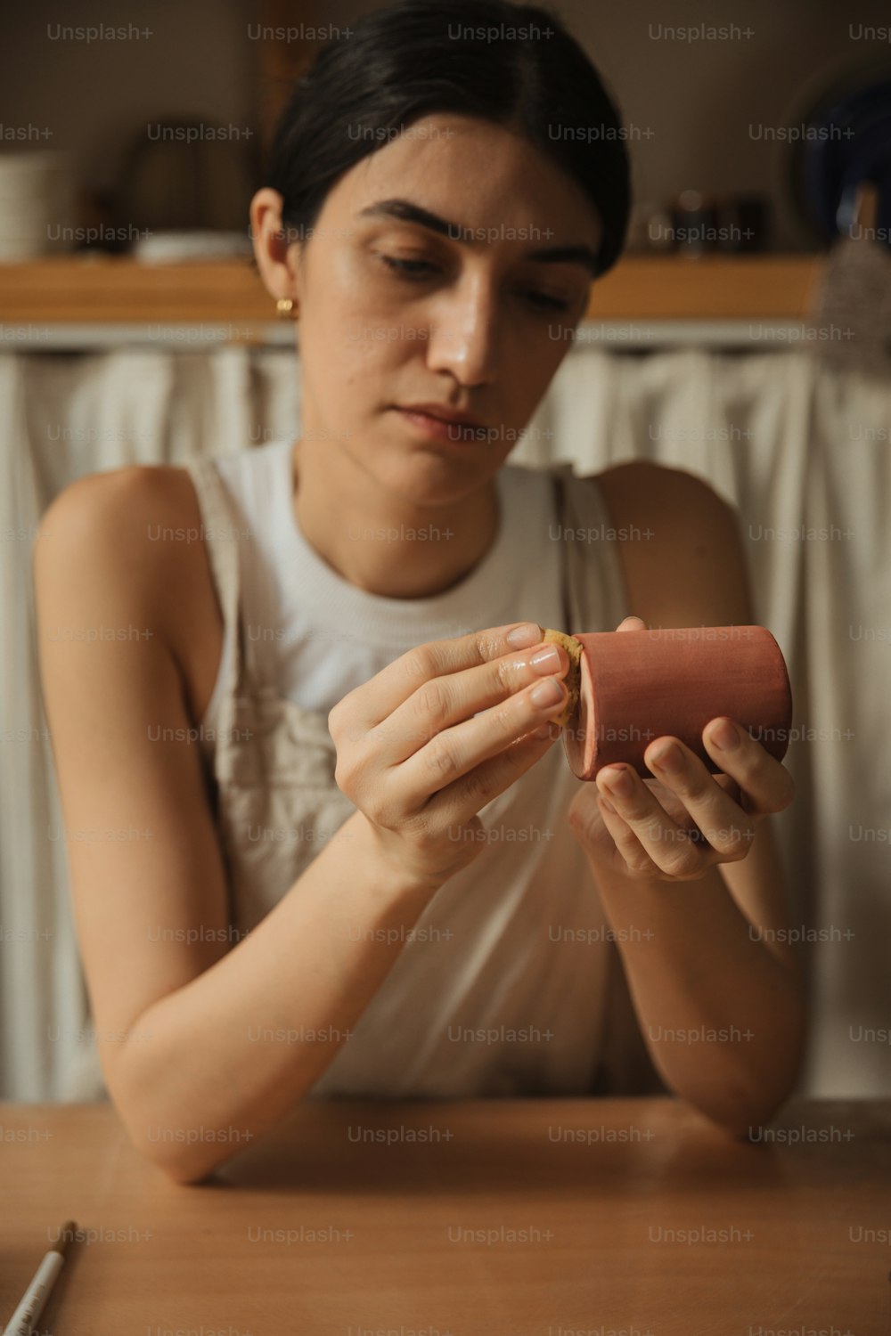 a woman sitting at a table holding a hot dog