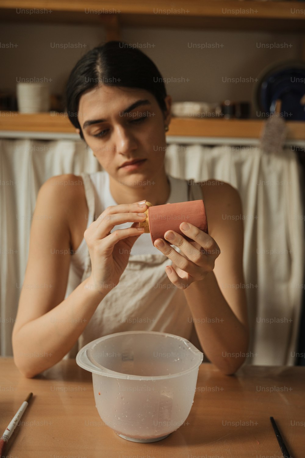 a woman sitting at a table holding a piece of food