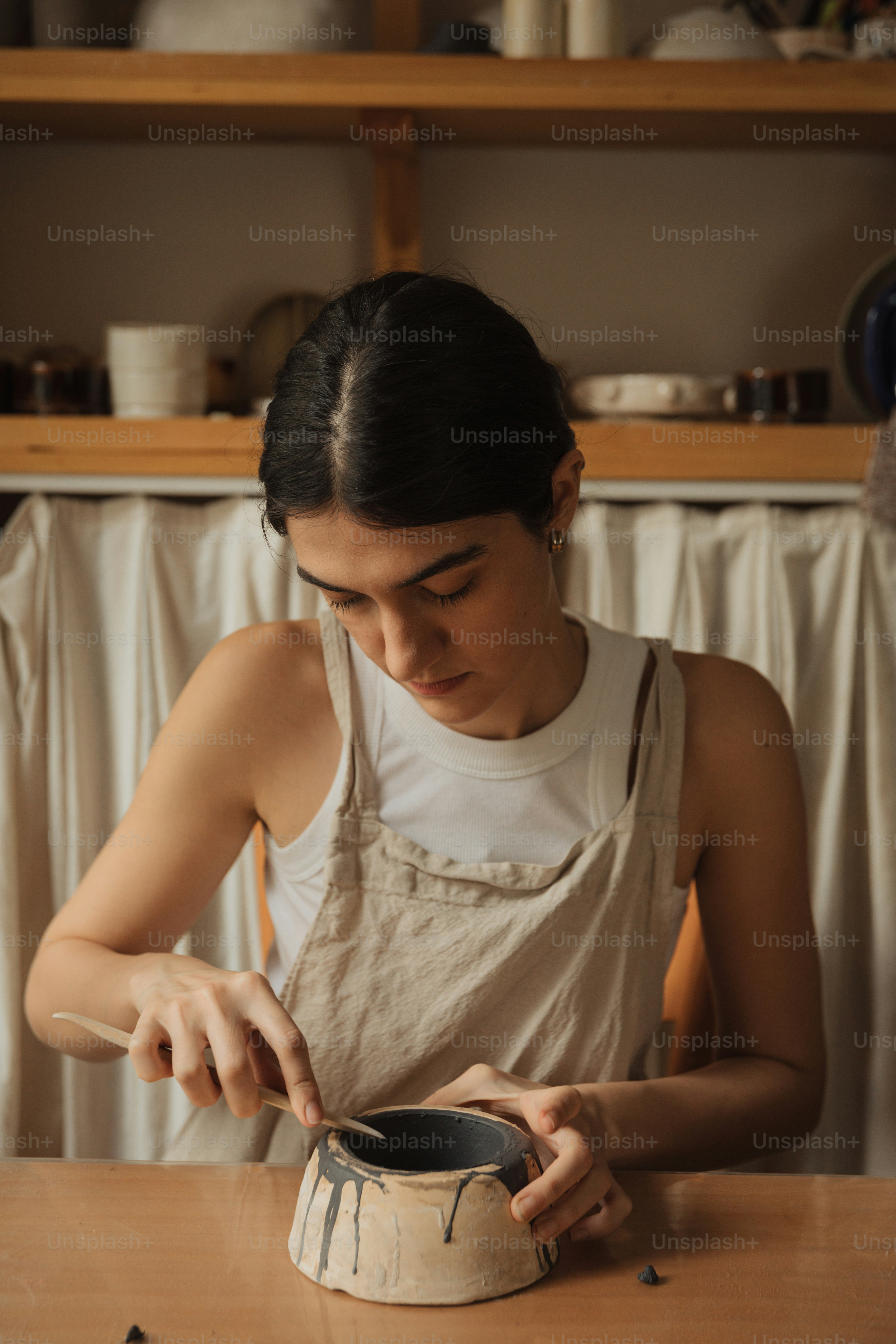 uma mulher sentada em uma mesa trabalhando em um vaso