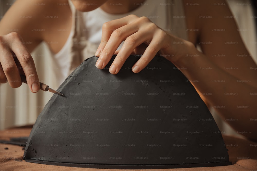 a woman is using a knife to cut a piece of stone