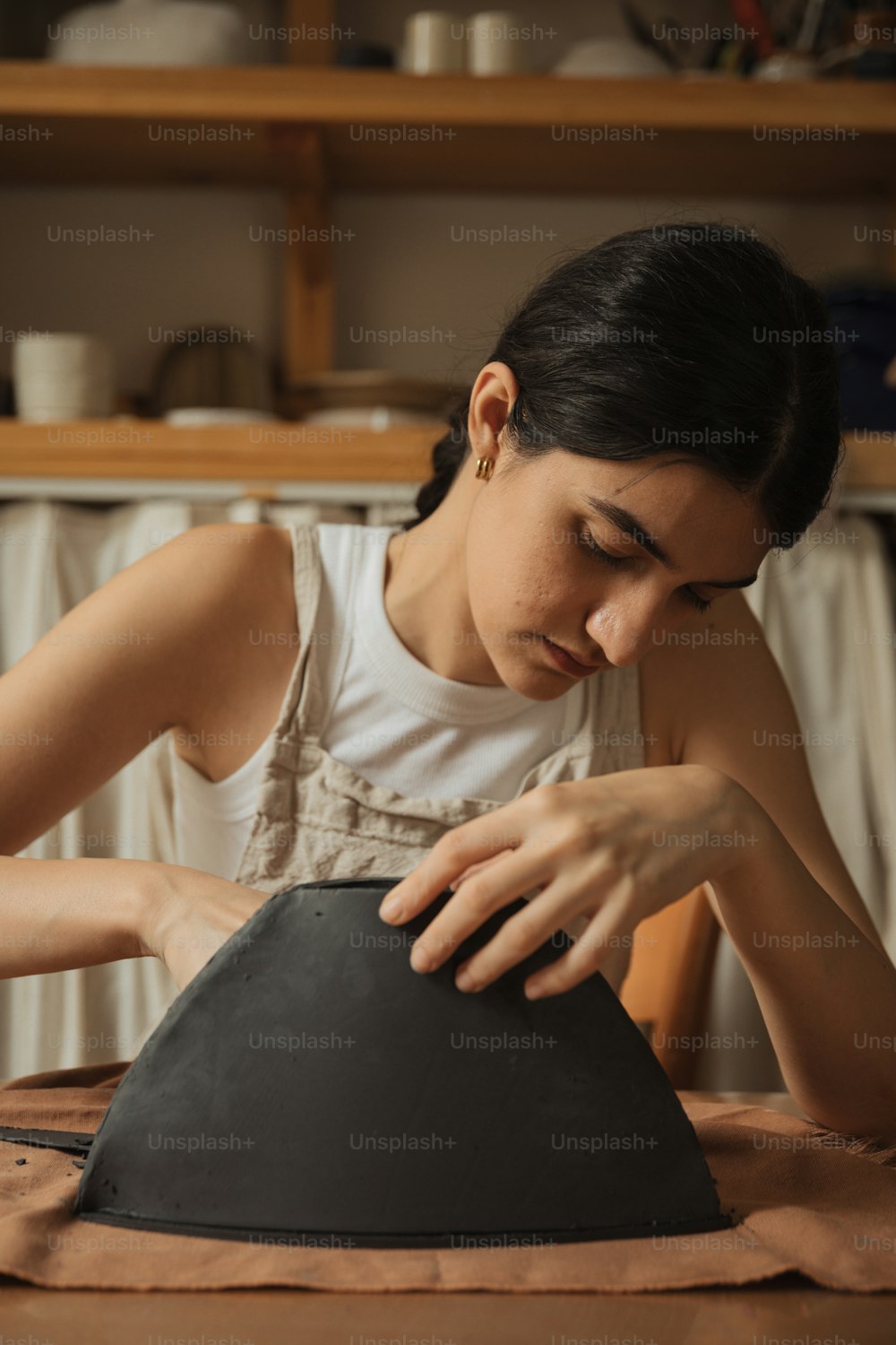 Una donna in camicia bianca sta lavorando su un oggetto nero