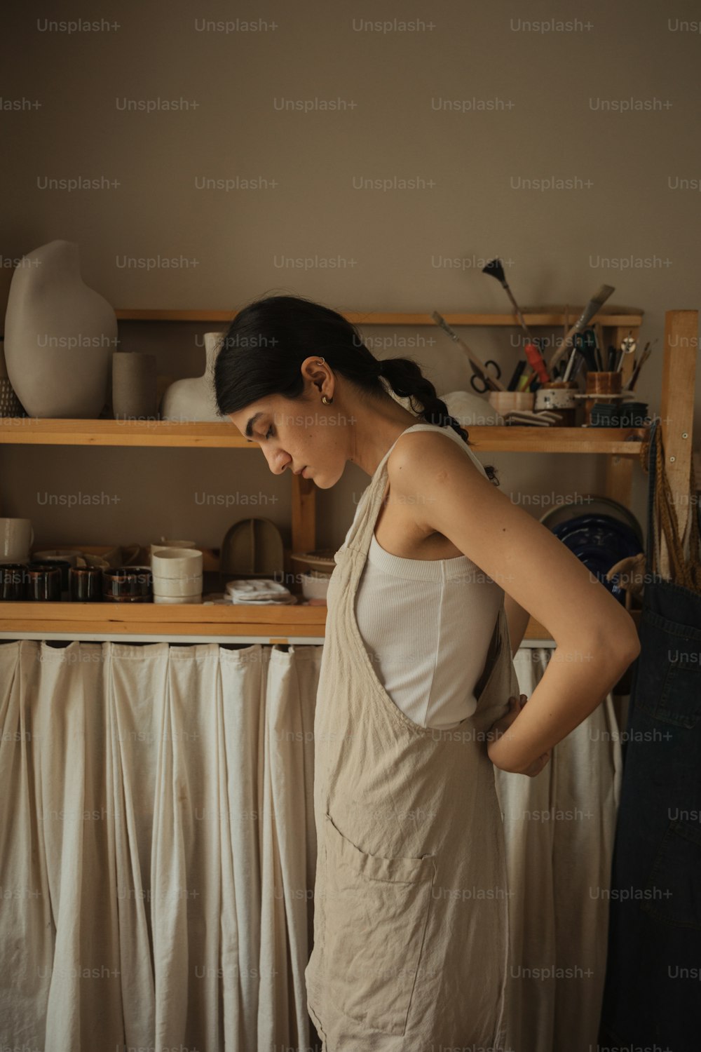 a woman standing in front of a shelf with dishes on it