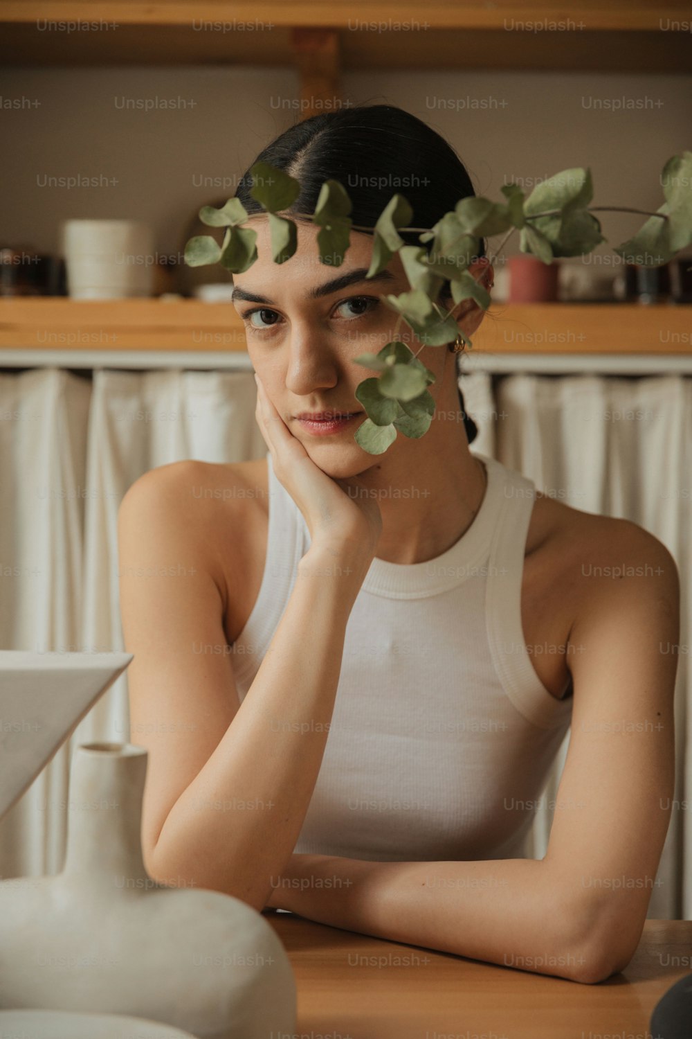 a woman sitting at a table with a plant on her head