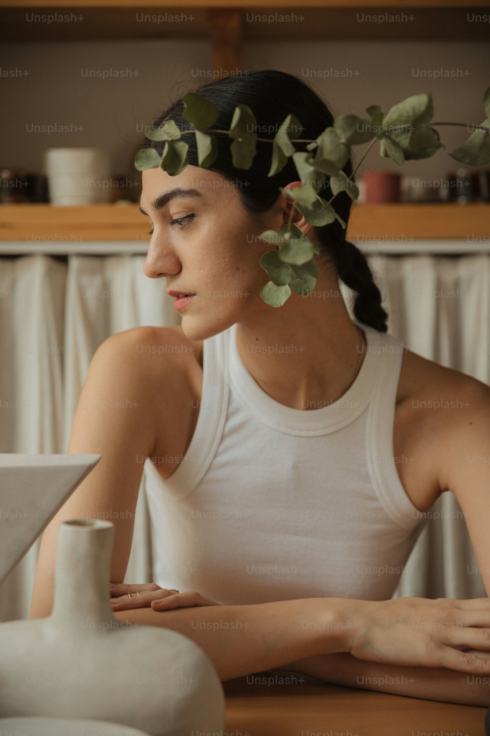 Eine Frau sitzt an einem Tisch mit einer Pflanze im Haar