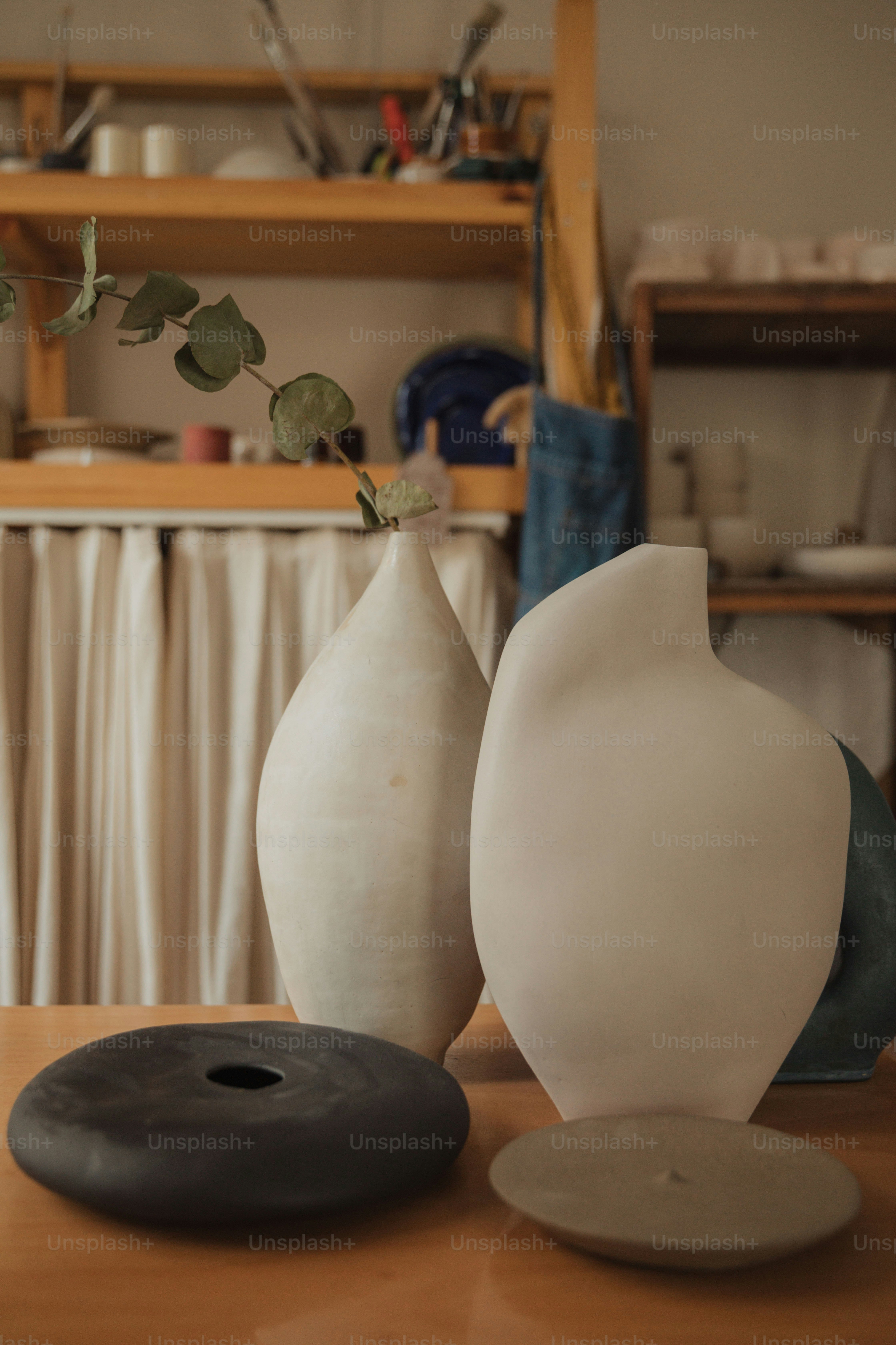 a couple of white vases sitting on top of a wooden table