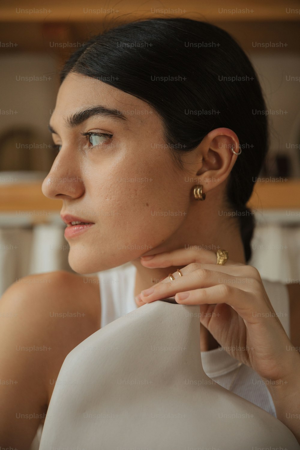 a woman in a white top is wearing a pair of earrings