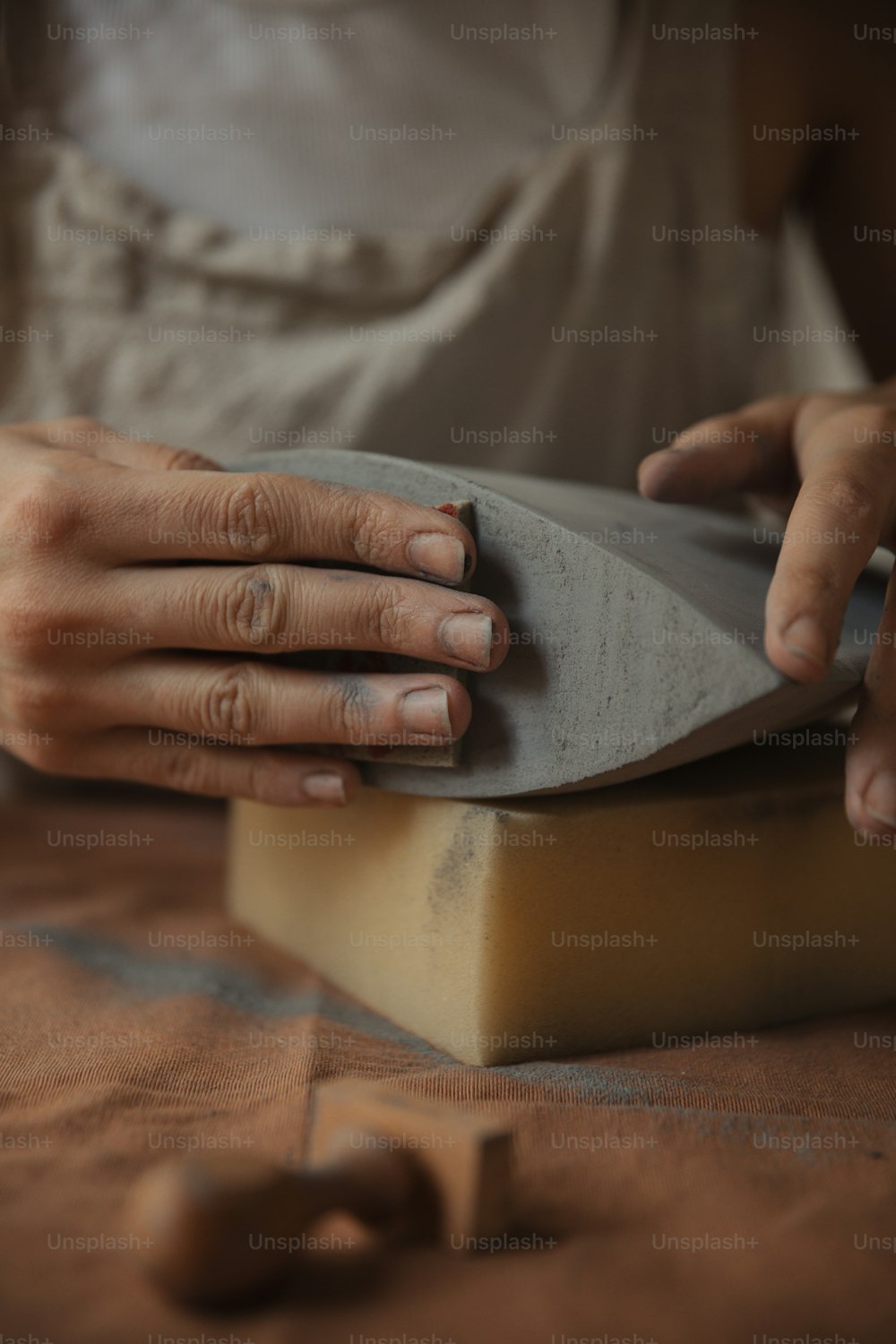 a close up of a person with their hands on a block of wood