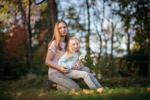 a woman and a little girl sitting in the grass