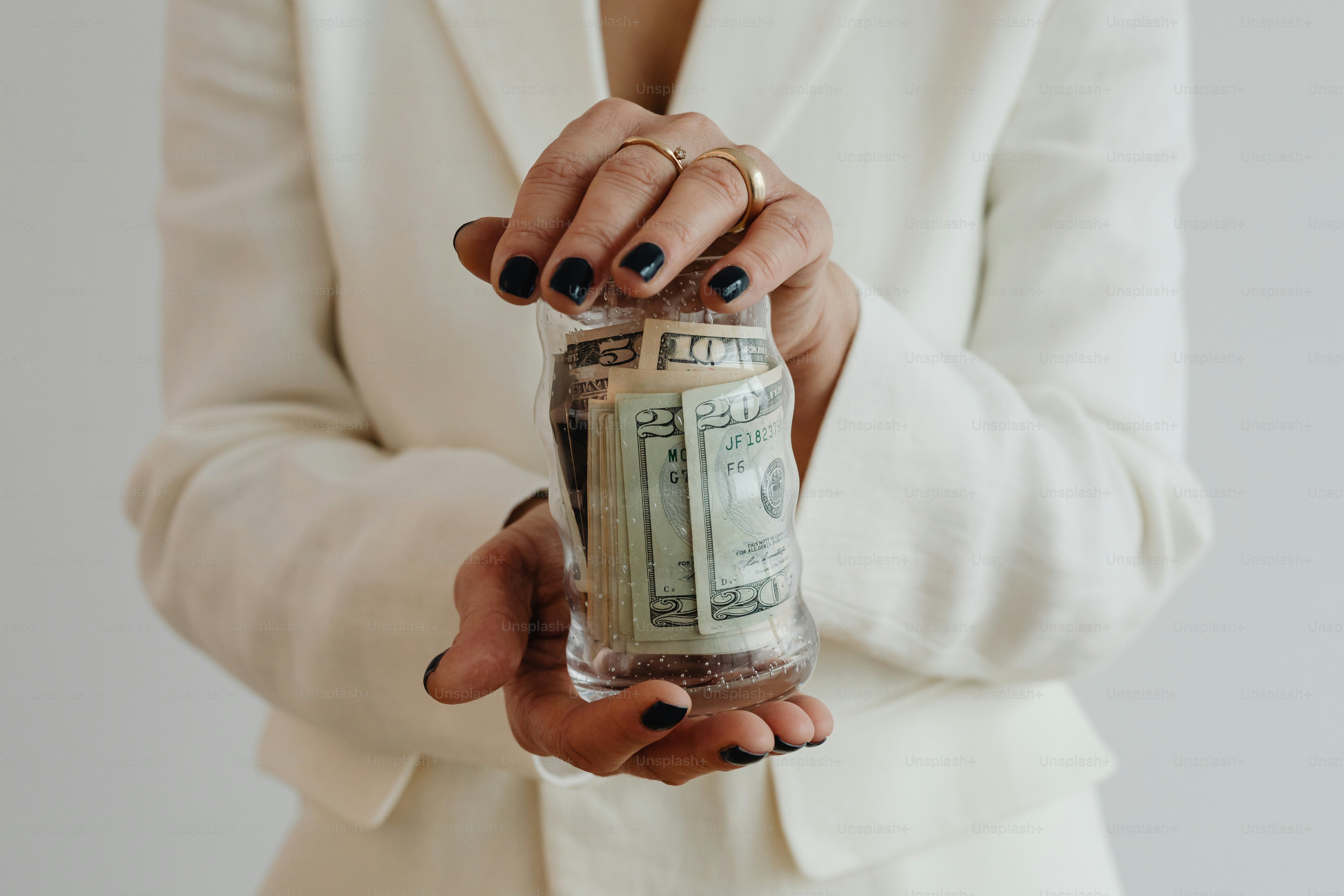 a woman in a white suit holding a jar of money