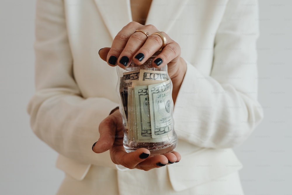 a woman in a white suit holding a jar of money