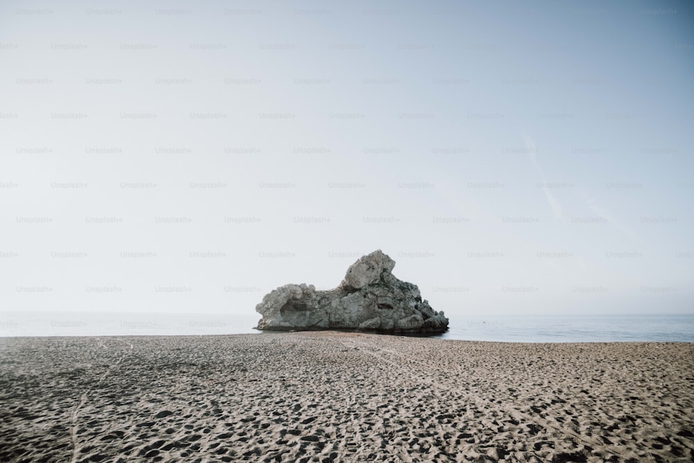 uma rocha saindo da areia em uma praia