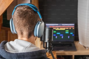 a young man wearing headphones looking at a computer screen