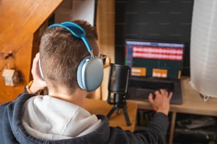 Ein junger Mann mit Kopfhörern und Blick auf einen Computerbildschirm